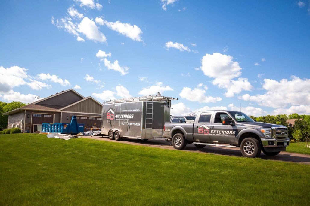 BD Exteriors truck and trailer outside a home working on a home exterior project