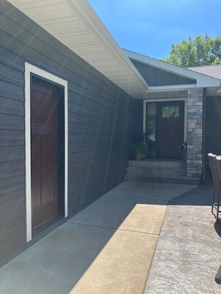 After image of a house with new blue siding windows and doors.