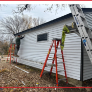 A worker repairing siding on a house.
