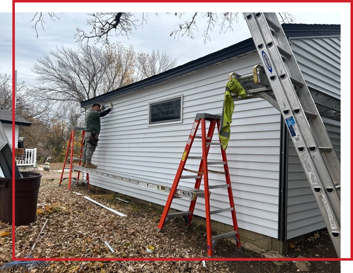 A worker repairing siding on a house.
