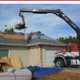 A crane holding up shingles for a new roof installation.