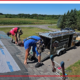 Two roofers work on installing new shingles on a home.