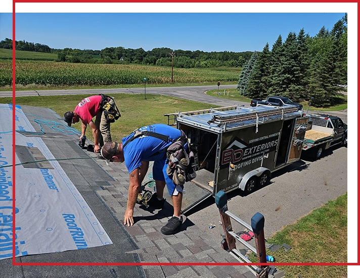 Two roofers work on installing new shingles on a home.